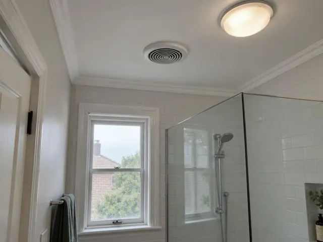Bathroom ceiling exhaust fan above tiled shower in a bright home bathroom in Woollahra